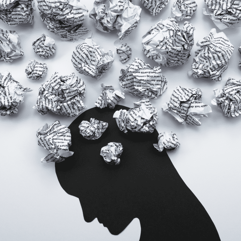 A silhouette of a person's head is depicted, surrounded by crumpled pieces of paper. The composition conveys a sense of chaos or overthinking.